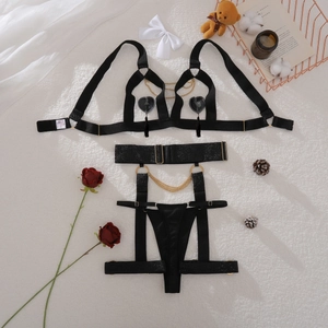 Detail of black hollow out lingerie set with golden metal chains and heart charms