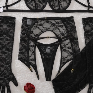 Flat lay of black floral lace lingerie set with garters and gloves on white faux fur