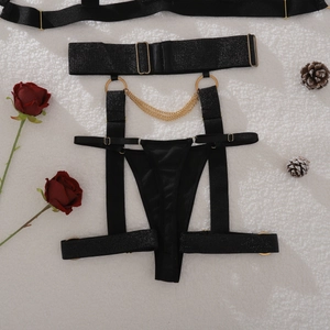 Detail of black lingerie set with golden metal chains and rings on white fur background