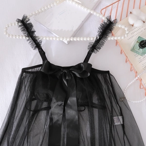 Détail d'un caraco noir en tulle transparent avec nœud en satin et bretelles volantées