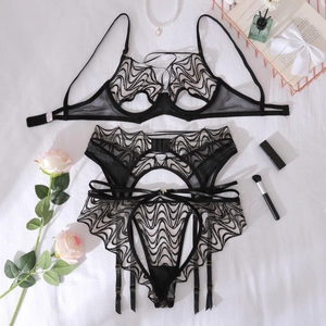 Flat lay of black lace lingerie set with garter belt, pearls, and pink roses decor