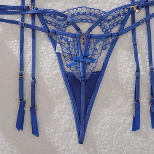 Close-up of blue lace garter belt with bow detail and gold adjustable clips on white fur