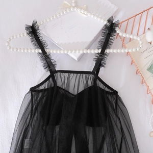 Détail d'un caraco en tulle noir à pois avec bretelles volantées sur fond élégant