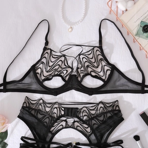 Flat lay of black sheer lace lingerie set with wavy texture on white fabric background