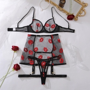 Detailed flat lay of sheer black mesh lingerie set with red lip embroidery and garter belt
