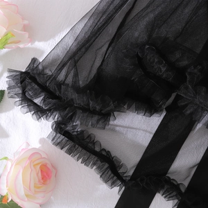Détail de tulle noir transparent avec volants et accents floraux pour un look romantique