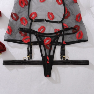 Detailed embroidery of red lips on black mesh lingerie set with golden hardware