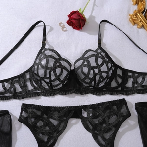 Flat lay of black lace lingerie set with heavy embroidery on white textured fabric background