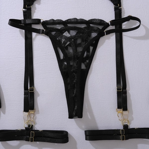 Detailed view of intricate black floral lace embroidery and gold metal rings on lingerie set