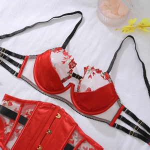 Detail of red rose embroidery on a satin corset with delicate metallic gold buckles
