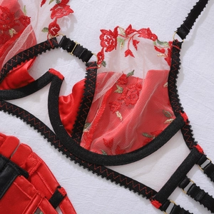 Close-up of red rose floral embroidery and black lace trim on a structured lingerie set