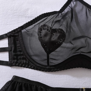 Detail view of sheer mesh lingerie with satin heart patches and sparkling black rhinestones
