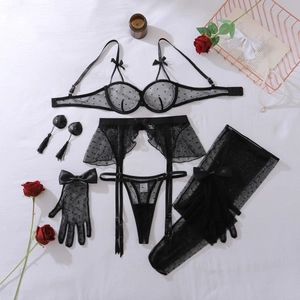 Set lingerie in pizzo nero a pois con fiocco e accessori romantici disposti in piano