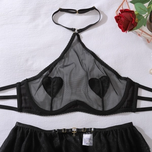 Detailed view of black mesh lingerie set with heart patches on a white fabric background