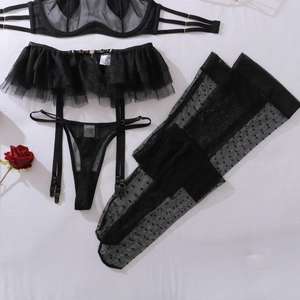 Detailed flat lay of black mesh lingerie set with polka dot stockings and a red rose
