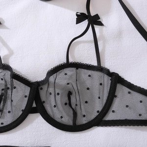 Dettaglio del reggiseno in mesh nero trasparente con pois e piccoli fiocchi decorativi