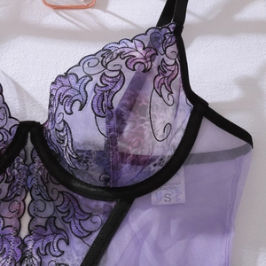 Dettaglio di lingerie in mesh viola con ricamo e bordo nero in vista piatta