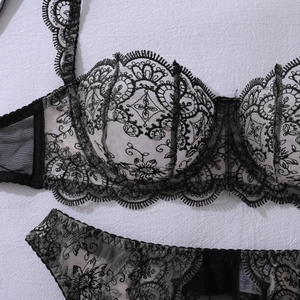 Detail of sheer floral embroidery on a black underwire lace bra with scalloped edges