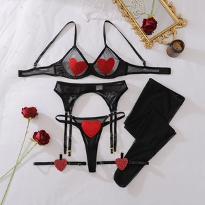 Flat lay of black mesh lingerie set with red heart sequins and stockings on beige background