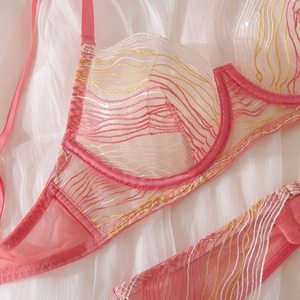 Detailed close-up of pink mesh lingerie with white and yellow wavy embroidery details