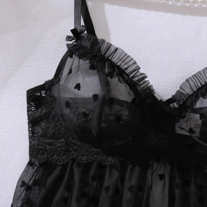 Dettaglio di lingerie in mesh nero con stampa a cuori e pizzo cigliato raffinato
