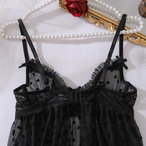 Dettaglio di lingerie in pizzo nero con motivo a cuori su sfondo di tessuto bianco