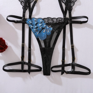 Détail de la broderie plume de paon bleue sur porte-jarretelles en dentelle noire et métal