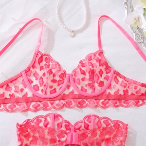 Detailed flat lay of pink lace lingerie set with heart patterns and floral props