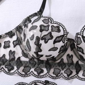 Detailed close-up of white lingerie cup with elegant black floral lace embroidery