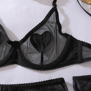Détail de la lingerie en maille noire avec découpes en forme de cœur et boucles dorées
