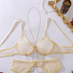 Detailed flat lay of pale yellow lace lingerie set with elegant gold metal body chains