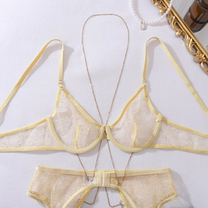 Detail of sheer yellow lace bra and panty set with golden chains and floral embroidery