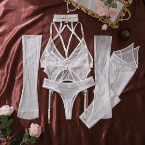 Detailed flat lay of white mesh lingerie set with golden hardware on silk background