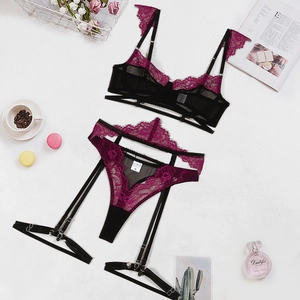 Flat lay of purple lace and black mesh lingerie set with garter belt and accessories