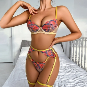 Detail view of yellow floral embroidery and sheer mesh lace on a 3-piece lingerie set