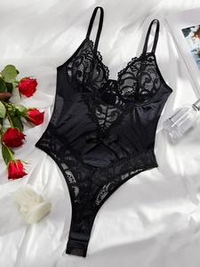Detail of black lace bodysuit with satin bow on a white silk background with red roses