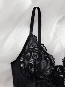 Detailed view of floral lace pattern and satin finish on black one-piece lingerie