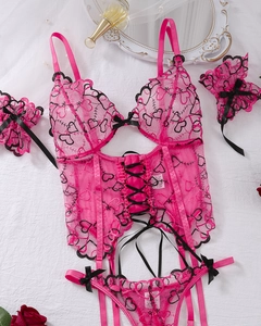 Flat lay of pink lace lingerie set with heart embroidery and vintage decorative props