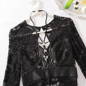 Détail d'un body en dentelle noire avec laçage croisé et anneaux en métal doré