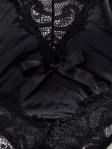 Close-up of black floral lace and satin texture featuring a delicate ribbon bow detail