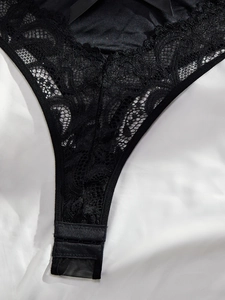 Detail of black lace bodysuit featuring floral embroidery and triple hook-and-eye closure