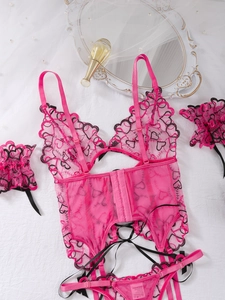Flat lay detail of pink lace lingerie set with black heart embroidery and ribbon bows
