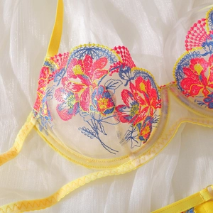 Detailed embroidery on yellow lace bra featuring vibrant pink and blue floral patterns