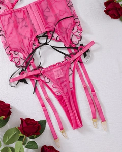 Flat lay of pink mesh lingerie set with black heart embroidery and ribbon details