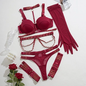 Détail d'un ensemble de lingerie en satin rouge avec chaînes dorées et gants en tulle