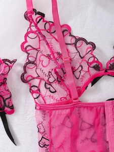 Detail of rose pink lace lingerie with heart embroidery and golden metal buckles