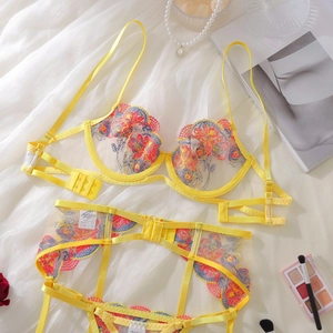 Detailed close-up of yellow floral embroidery on sheer mesh lingerie set with garter belt