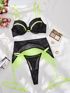 Detailansicht der neongrünen und schwarzen Lingerie mit Stickerei und Strapsgürtel