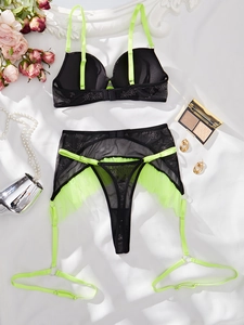Details des schwarzen Mesh-Dessous-Sets mit Blumenstickerei und neongrünen Akzenten
