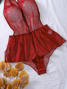 Detailed macro view of red mesh bodysuit with waist size S label and triple snap closure